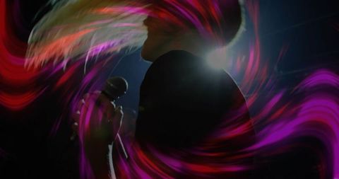 Dynamic female singer performing with magenta light trails and backlit silhouette on stage