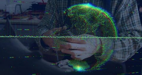 Holding smartphone displaying holographic globe with digital data overlay, futuristic workspace