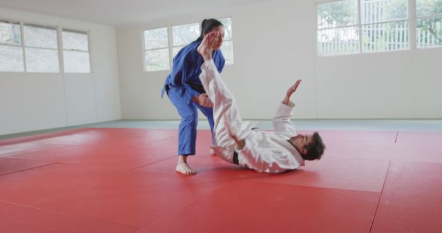Judo practitioners training together in dojo, engaging in throwing techniques. This dynamic image can be used for promoting martial arts classes, fitness programs, or sports events.