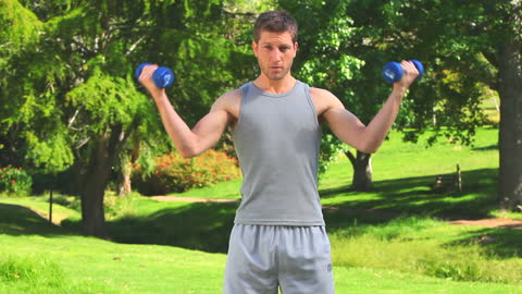 Man Lifting Dumbbells Outdoors in Park Setting