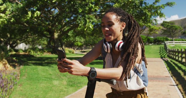 Young Woman Riding Scooter in Park Checking Smartphone - Download Free Stock Images Pikwizard.com