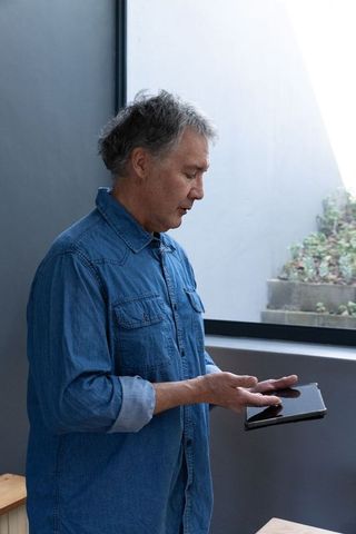 Mature man holding tablet in modern home office