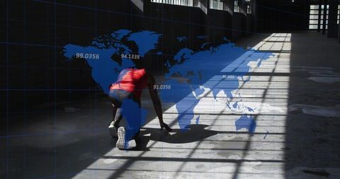 Athlete preparing to sprint in industrial warehouse with global map overlay and dramatic shadows