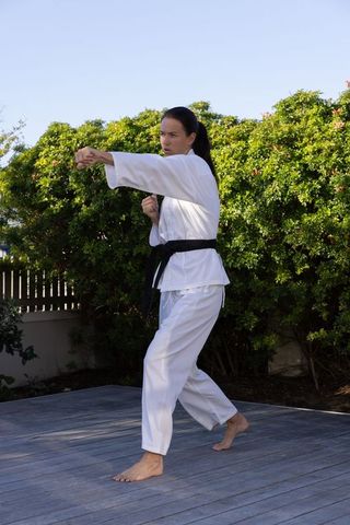 Martial Artist Practicing Punch Technique Outdoors in White Gi