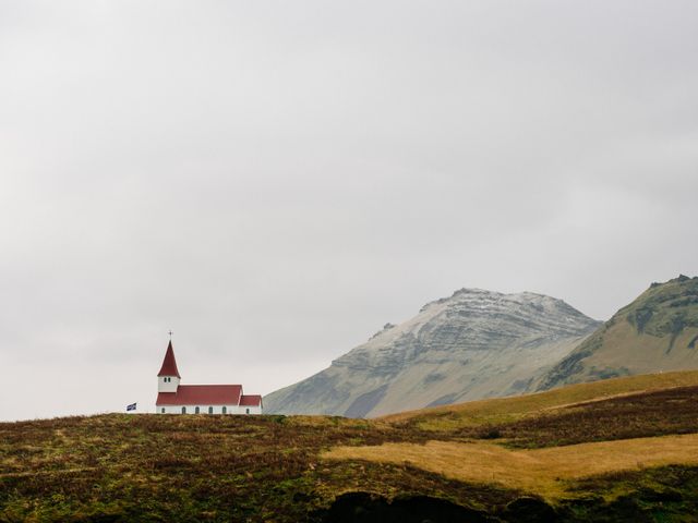White church with red roof stands alone against an overcast sky and mountainous backdrop. This image can be used for themes of isolation, tranquility, rural life, religious devotion, and architecture in natural settings. Ideal for travel ads, religious contexts, and nature photography collections.