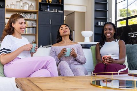 Three black african women enjoying cozy coffee chat in modern living room