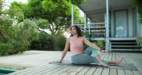 Woman Practicing Yoga on Deck by Pool for Wellbeing and Relaxation