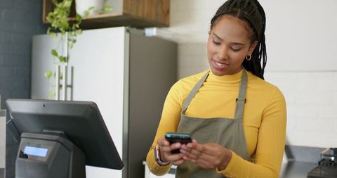 Barista using smartphone for mobile payment at modern cafe POS counter