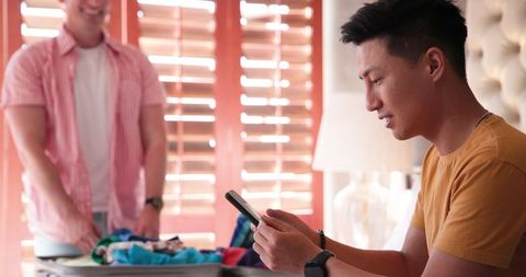 Diverse male couple sharing bond over folding laundry at home