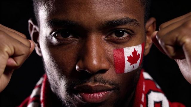 Intense canadian sports fan wearing flag face paint and red scarf, determined closeup