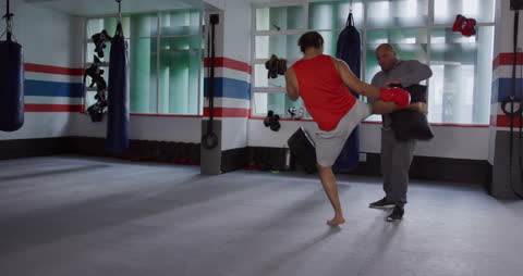 Kickboxer Practicing Powerful Kick Maneuver with Trainer