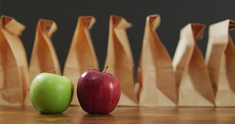 Lunch bags and fresh apples on wooden table for healthy eating