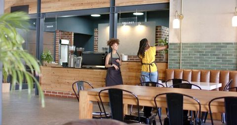Cafe team preparing counter and styling interior in rustic industrial coffeehouse