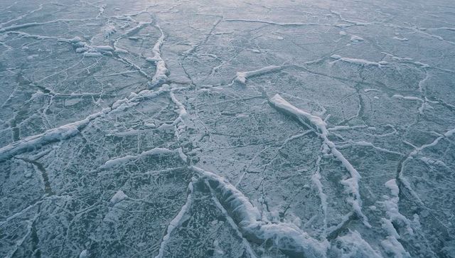 Sea ice forming pressure ridges and fractures over frozen bay with compacted snow texture