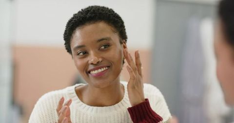 Smiling African American Woman Applying Skincare with Cozy Expression