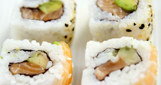 Close-up of sushi rolls with rice, avocado, and fish, showcasing the details of Japanese cuisine. Perfect for food enthusiasts looking to explore the art of sushi making.