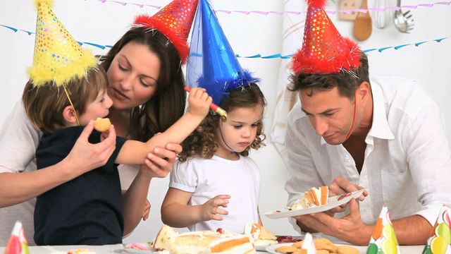 Parents with children celebrating birthday at home. Kids wearing colorful party hats. Cake and other treats on table. Can be used for family celebrations, party planning, festive events, and parenting themes.