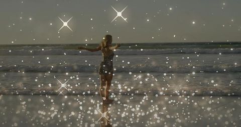 Woman Embracing Ocean Sunset with Bokeh Star Flares and Wet Sand Reflection