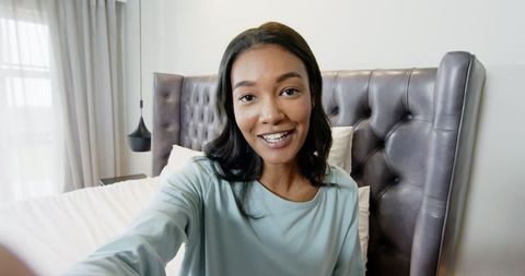 African american woman recording vlog in bright minimalist bedroom
