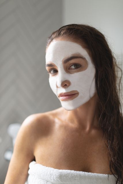 Portrait of woman with facial mask standing in bathroom at home