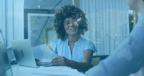 Smiling consultant reviewing reports with laptop and digital world map overlay