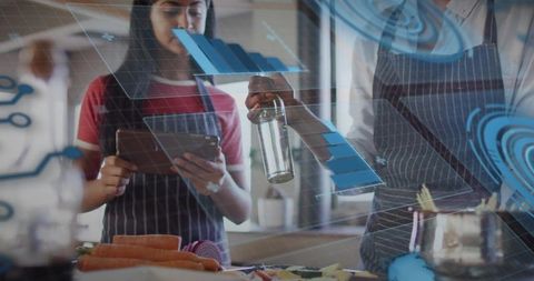 Teen and adult using tablet with augmented reality cooking data while preparing vegetables