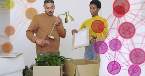 Young couple unpacking boxes and arranging lamp and frame during bright move-in day