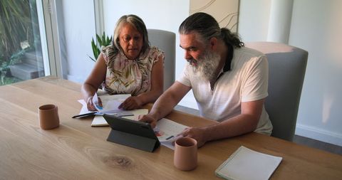 Senior Couple Discussing Finances While Using Tablet at Home