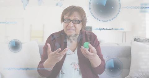 Mature woman holding pill bottle gesturing during telehealth consult with hud overlay