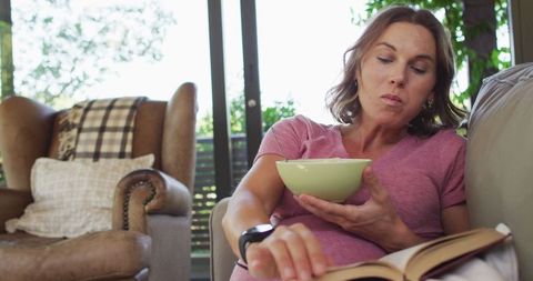 Pregnant Woman Enjoys Reading and Snacking at Home