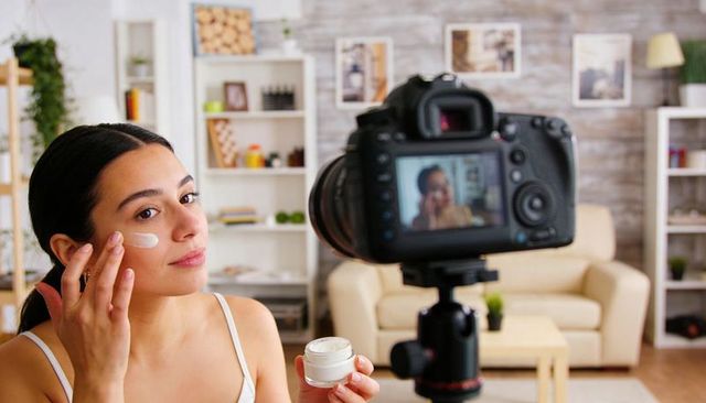 Applying moisturizer while filming beauty vlog, skincare creator recording at home