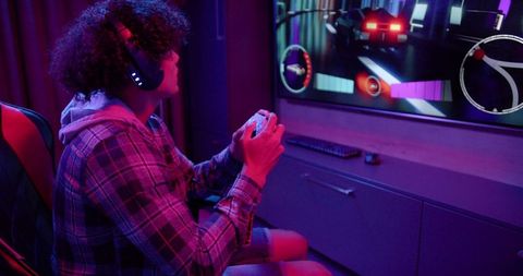 Curly-haired gamer engaged in intense video game racing at home