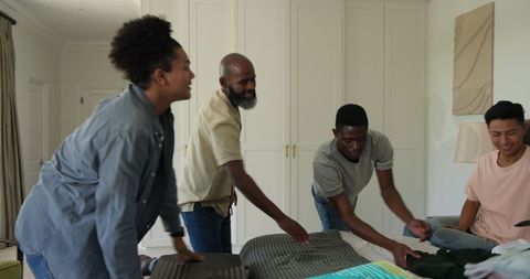Friends packing for destination celebration in bedroom