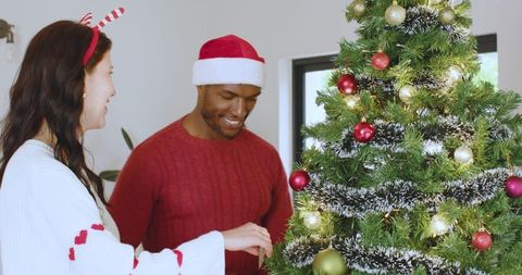 Couple Joyfully Decorating Christmas Tree with Baubles