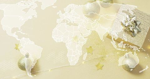 Gold holiday map flatlay featuring wrapped gift box, glitter ornaments, string lights