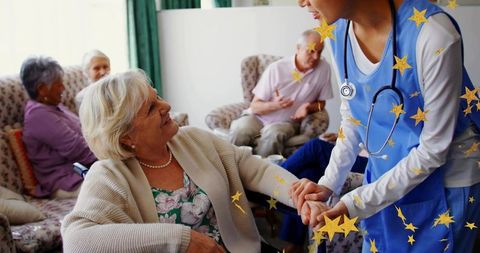Nurse holding hand of smiling senior woman in care home lounge offering compassionate support