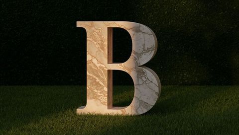 Large marble letter b sculpture on green lawn with shadowing