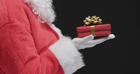 Hand of Santa Claus Holding Gift Box in Christmas Spirit