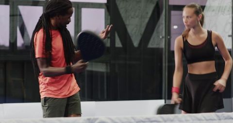 Man and Woman Engaged in Padel Tennis Match on Indoor Court