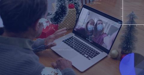 Senior Man Video Calling Masked Family on Laptop During Holiday Gathering