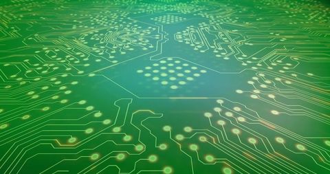 Close-up green printed circuit board displaying gold traces, solder pads and hex pad array