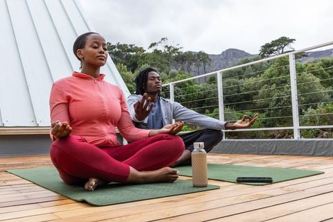 African american couple meditating on rooftop terrace practicing outdoor yoga mindfulness