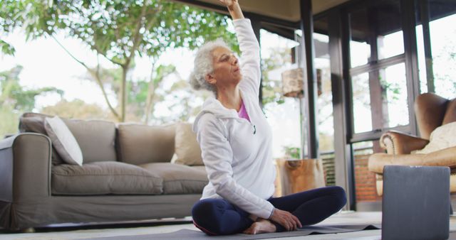 Senior biracial woman practicing yoga, stretching. retirement and senior lifestyle, spending time alone at home.