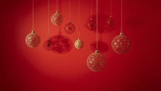 Hanging gold lattice baubles casting dramatic shadows on rich red luxury holiday backdrop