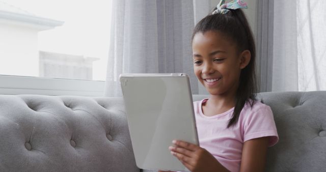 Smiling Young Girl Having Fun with Tablet on Sofa - Download Free Stock Images Pikwizard.com