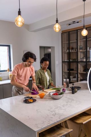 Asian man and african american woman preparing healthy meal at modern marble kitchen island