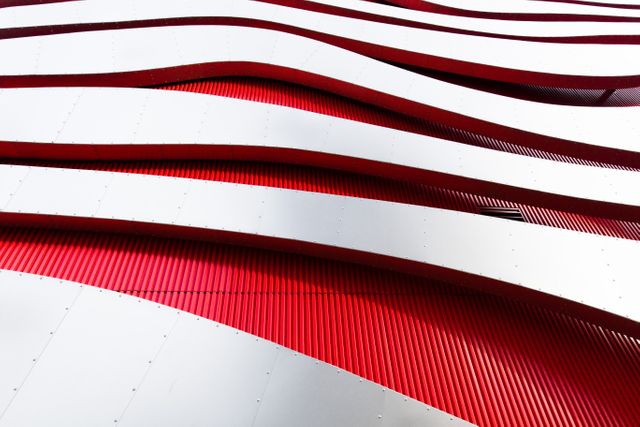 Modern architectural design featuring an abstract exterior facade with wavy red and white patterns. Perfect for use in articles about contemporary architecture, urban design trends, and modern building materials. Great for illustrating concepts of innovative design, structural creativity, and aesthetics in promotional materials or architectural portfolios.