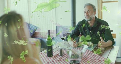 Middle-aged man gesturing while dining with partner at cozy sunlit wooden kitchen table
