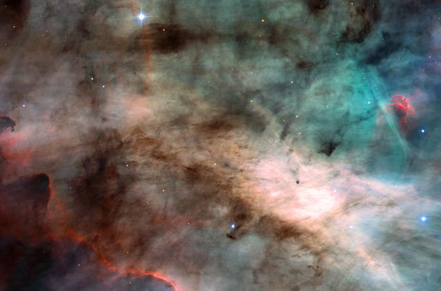 This sturning image, taken by the newly installed Advanced Camera for Surveys (ACS) aboard the Hubble Space Telescope (HST), is an image of the center of the Omega Nebula. It is a hotbed of newly born stars wrapped in colorful blankets of glowing gas and cradled in an enormous cold, dark hydrogen cloud. The region of nebula shown in this photograph is about 3,500 times wider than our solar system. The nebula, also called M17 and the Swan Nebula, resides 5,500 light-years away in the constellation Sagittarius. The Swan Nebula is illuminated by ultraviolet radiation from young, massive stars, located just beyond the upper-right corner of the image. The powerful radiation from these stars evaporates and erodes the dense cloud of cold gas within which the stars formed. The blistered walls of the hollow cloud shine primarily in the blue, green, and red light emitted by excited atoms of hydrogen, nitrogen, oxygen, and sulfur. Particularly striking is the rose-like feature, seen to the right of center, which glows in the red light emitted by hydrogen and sulfur. As the infant stars evaporate the surrounding cloud, they expose dense pockets of gas that may contain developing stars. One isolated pocket is seen at the center of the brightest region of the nebula. Other dense pockets of gas have formed the remarkable feature jutting inward from the left edge of the image. The color image is constructed from four separate images taken in these filters: blue, near infrared, hydrogen alpha, and doubly ionized oxygen. Credit: NASA, H. Ford (JHU), G. Illingworth (USCS/LO), M. Clampin (STScI), G. Hartig (STScI), the ACS Science Team, and ESA.