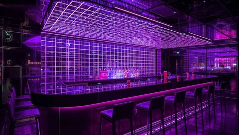Neon-lit glossy bar counter with LED grid ceiling, mirrored shelves and bottle display